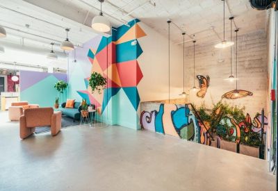 Spacious communal lounge with mid-century furniture and geometric wall mural.