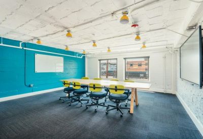 Large meeting room with a teal accent wall, whiteboard, and yellow-accented chairs.