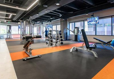 Modern fitness center with weight machines and orange floor accents.