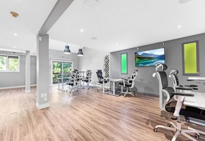 Open-plan office with grey walls, green wall accents, and multiple ergonomic workstations.