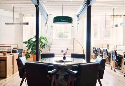 Meeting area with black leather chairs around a square table and industrial pillars.