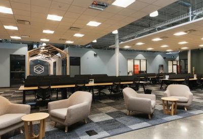 Open-plan office with rows of wooden desks and comfortable lounge armchairs.