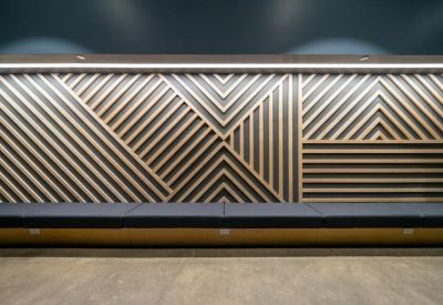 Feature wall with a geometric light wood pattern behind a long dark cushioned bench.