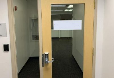 Wooden entrance door with glass panels leading into a carpeted office suite.