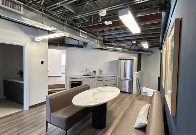 Modern communal dining area with leather banquette seating and exposed ceiling joists.