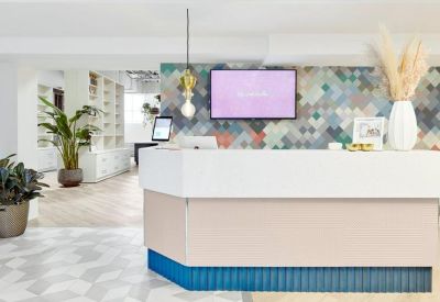 Minimalist white reception desk with a colorful geometric feature wall.