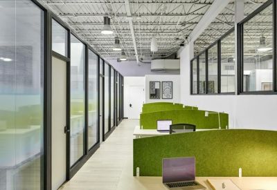 A hallway of private glass-walled offices with green acoustic privacy screens.