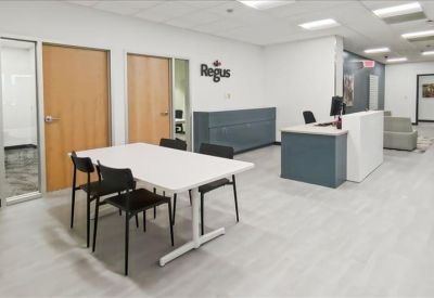 Spacious reception area with a blue and white front desk and wooden doors.