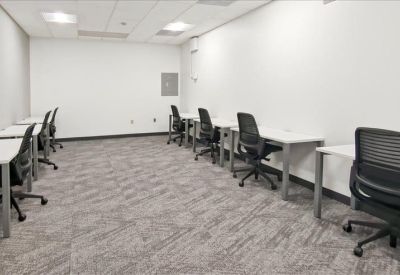 Spacious workstation area with multiple white desks and black ergonomic chairs.