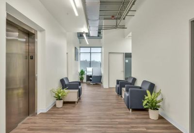 Modern lobby with blue armchairs, wood-style flooring, and potted plants.