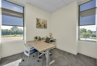 Private windowed office with a wooden desk and a view of greenery.