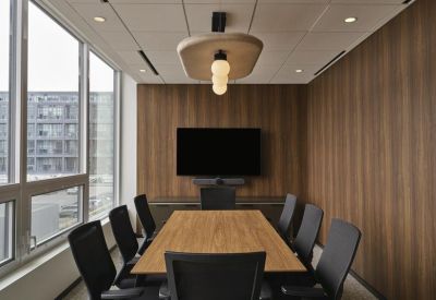 Sunlit meeting room with wood-paneled walls and a large monitor.