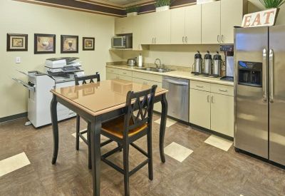 Modern office kitchen and breakroom featuring a stainless steel fridge and coffee station.
