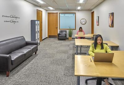 Spacious coworking area with a leather sofa, lockers, and natural wood desks.