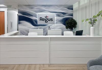 Private two-person office suite with light wood desks and large windows overlooking trees.