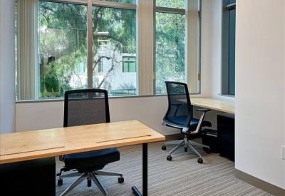 Spacious boardroom with a long wood table, white chairs, and video conferencing screen.