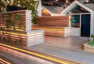 Spacious tiered lounge with wooden slats, integrated lighting, and indoor plants.