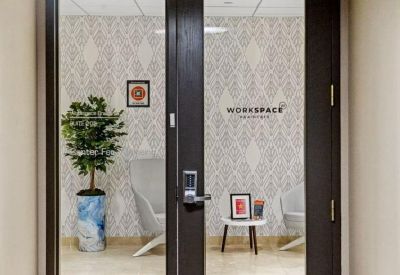Modern glass entrance with workspace branding and pattern wallpaper.