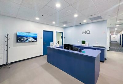 Blue reception desk at the entrance of the office with the HQ logo on the wall.