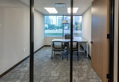Private glass-walled office suite with two workstations and views of the city skyline.