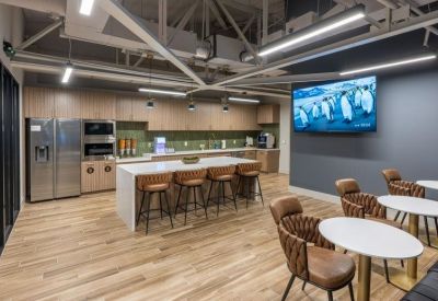 Modern breakroom and kitchen at 1500 Waugh Drive with island seating and a large wall-mounted screen.