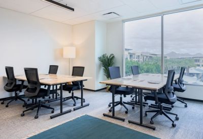 Modern office space with two large wooden desks and ergonomic black chairs.