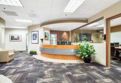 Modern reception area featuring a curved wood and metal desk and patterned carpet.