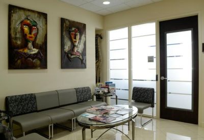 Reception waiting area featuring a grey sectional sofa and abstract portrait artwork.