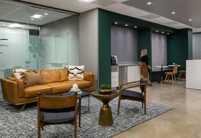 Lounge area with a tan leather sofa, accent chairs, and a green feature wall.