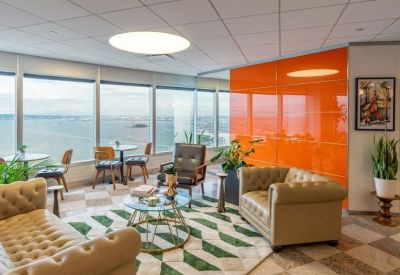 Bright lounge with tufted leather sofas, a patterned rug, and floor-to-ceiling harbor views.