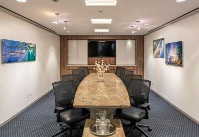 Sophisticated boardroom with a stone-top table, leather chairs, and colorful artwork.