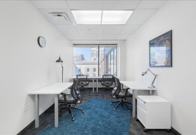 Internal four-person office suite with white desks and a blue area rug.