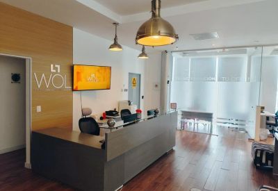 Modern reception area with wood paneling, warm pendant lighting, and a grey front desk.
