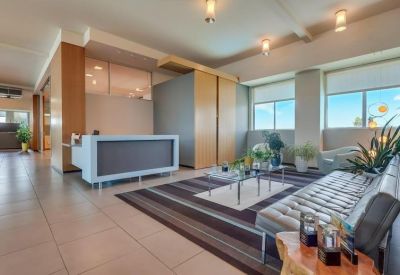 Bright lounge area with a striped rug, plush grey sofa, and large windows.
