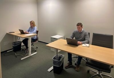 Private two-person office suite with light wood desks and grey carpeting.