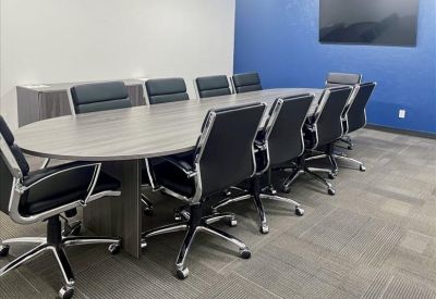 Large boardroom with an oval wood table, black leather chairs, and a blue accent wall.