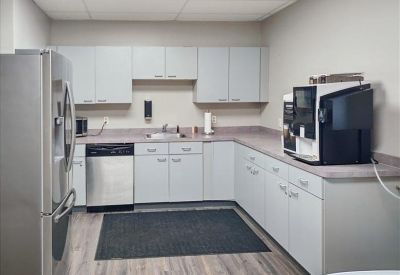 Clean communal kitchen with grey cabinetry, stainless steel appliances, and a coffee machine area.