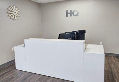 Bright reception area with a minimalist white front desk and 'HQ' logo on the wall.