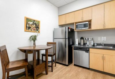 Communal kitchen with wooden cabinets, stainless steel appliances, and a dining table.