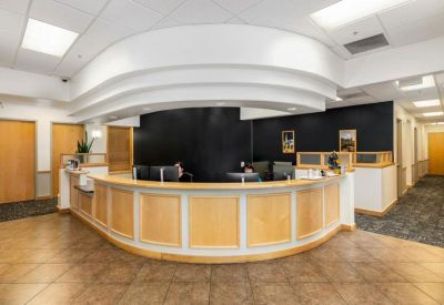Curved wood reception desk in a bright lobby with tiled floors.
