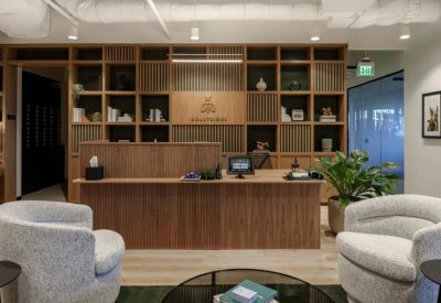 Wood-paneled reception desk featuring the Industrious logo and decorative shelving with greenery.