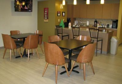 Communal kitchen and breakroom area with several dining tables and wooden chairs.