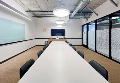 Professional meeting room featuring a light wood table, stylish teal chairs, and a media wall.