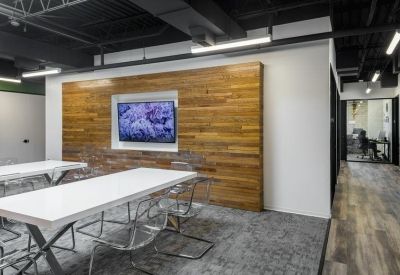 Bright workspace featuring white tables, clear acrylic chairs, and a natural wood-paneled accent wall.