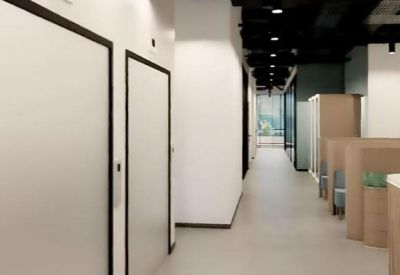 Modern office hallway leading past wood-paneled privacy booths and workstations.