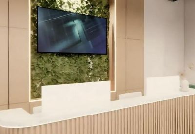 Bright reception desk with light wood paneling and a vibrant green living plant wall.