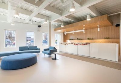 Reception area with a sleek white front desk and wood-paneled wall accents.