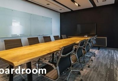 Long wooden boardroom table with modern black mesh chairs and a large whiteboard.
