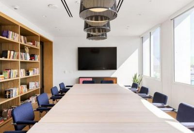 Professional meeting room with a large wooden table, blue chairs, and a floor-to-ceiling bookshelf.