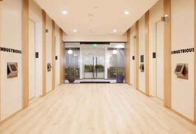 Bright elevator lobby with light wood paneling and glass doors leading to the office.